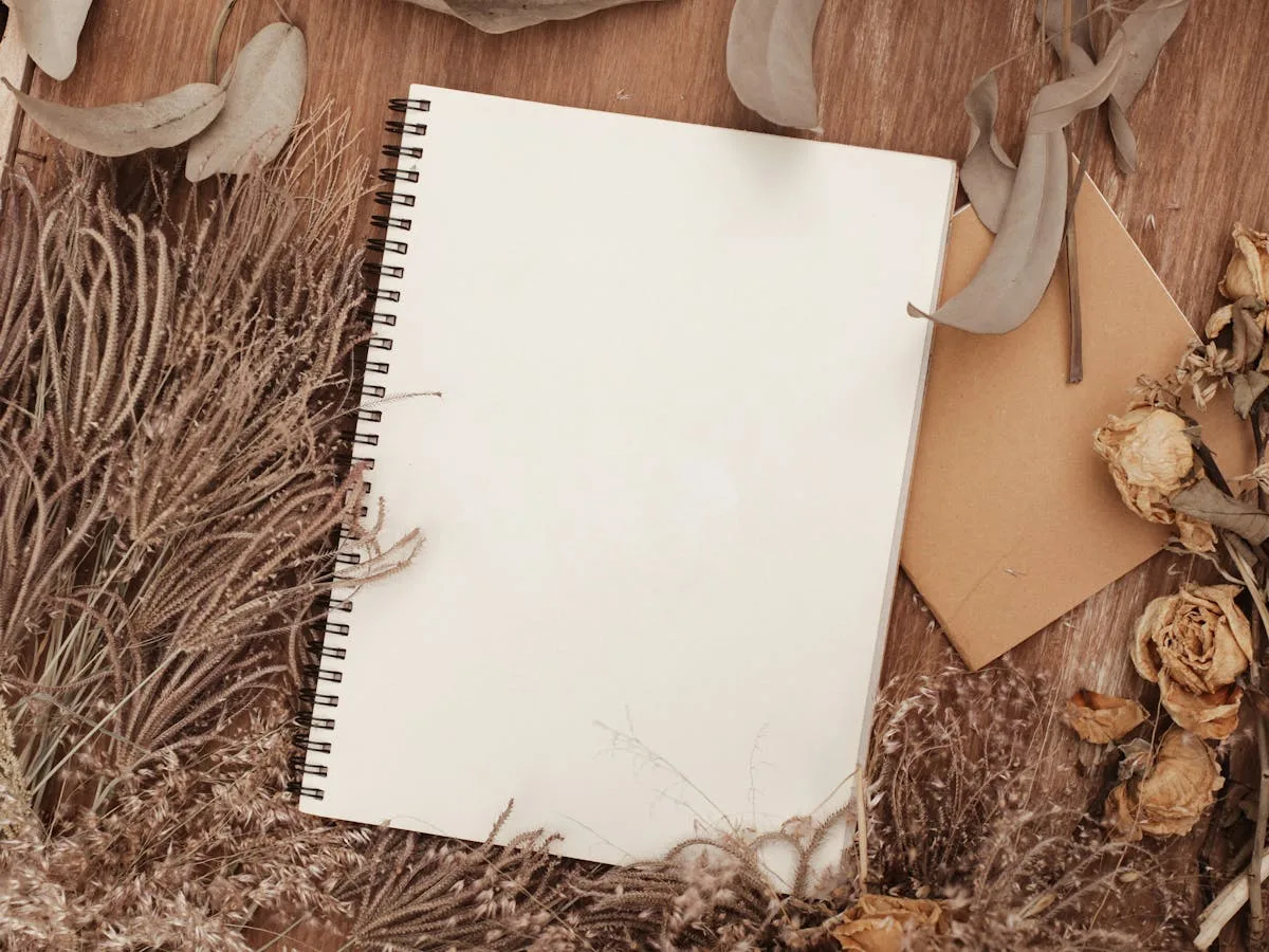 Soft cottagecore flatlay with dried flowers, a journal, and neutral paper for an aesthetic vision board