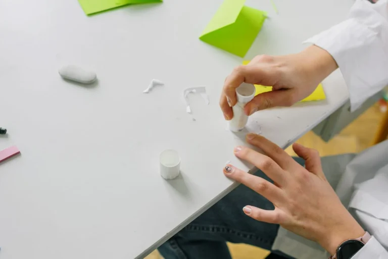 Hands applying glue from a glue stick during a paper craft project