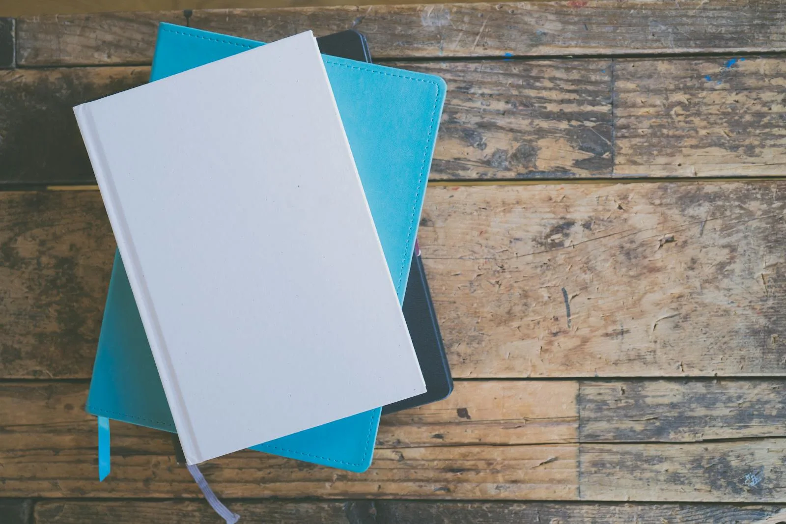 Stack of blank journals on a rustic wooden table