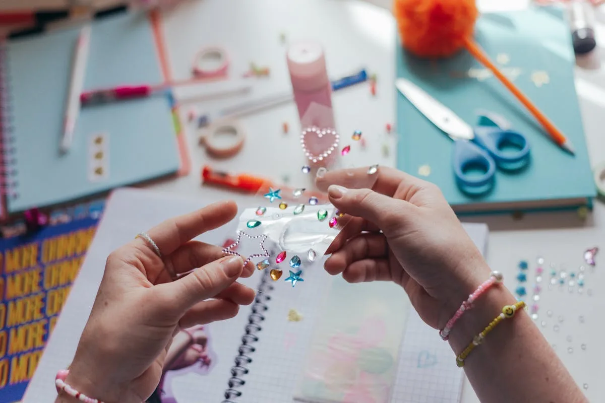 Hands arranging paper and decorations on a creative journal spread