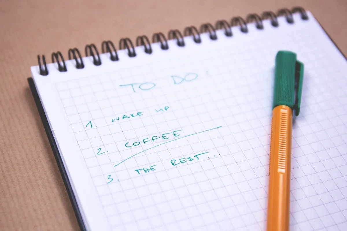 A daily to-do list written in a notebook with a pencil