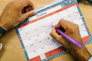 Person writing a weekly planner spread in a notebook