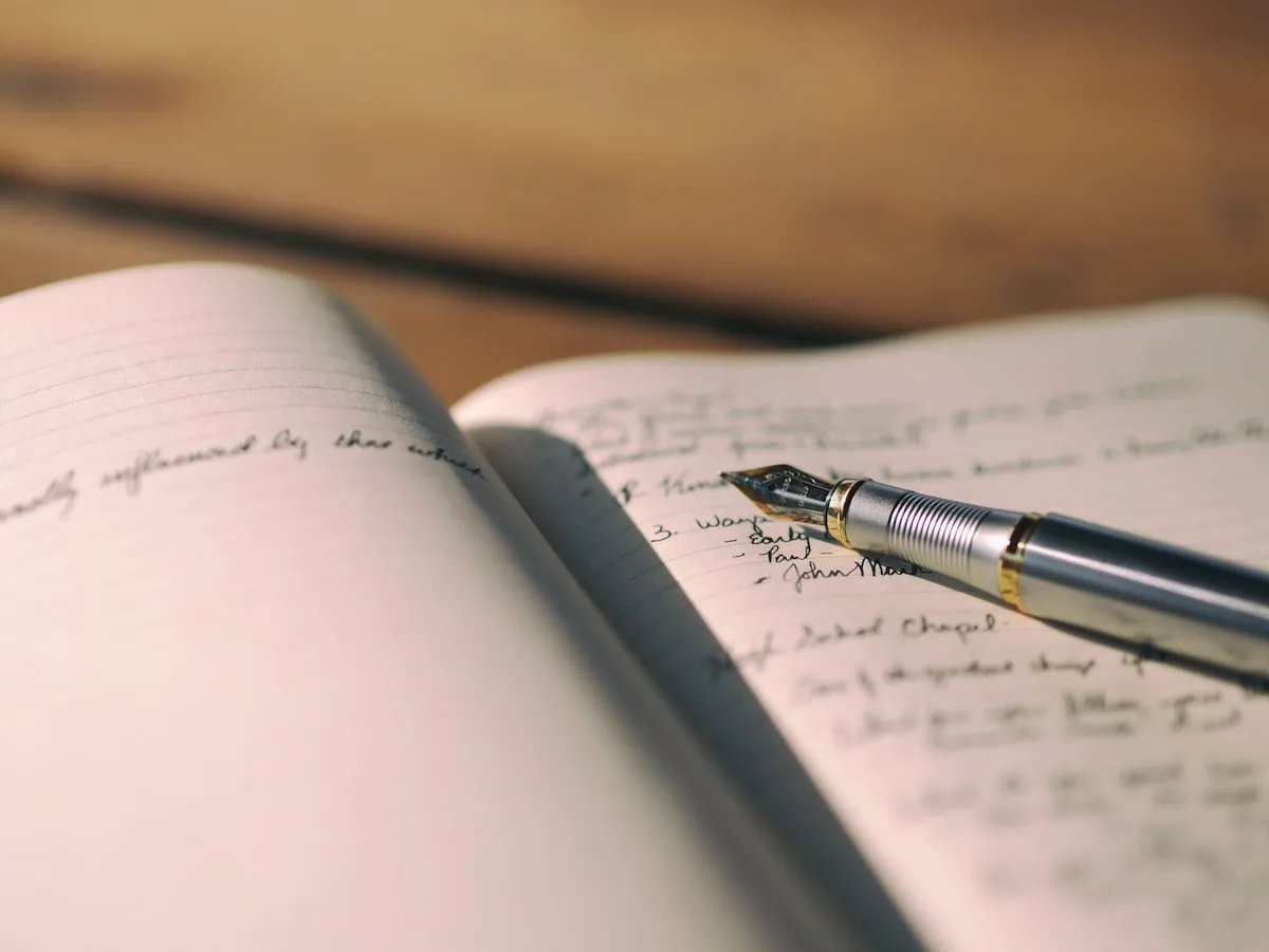 Open dotted bullet journal with a pen on a wooden desk