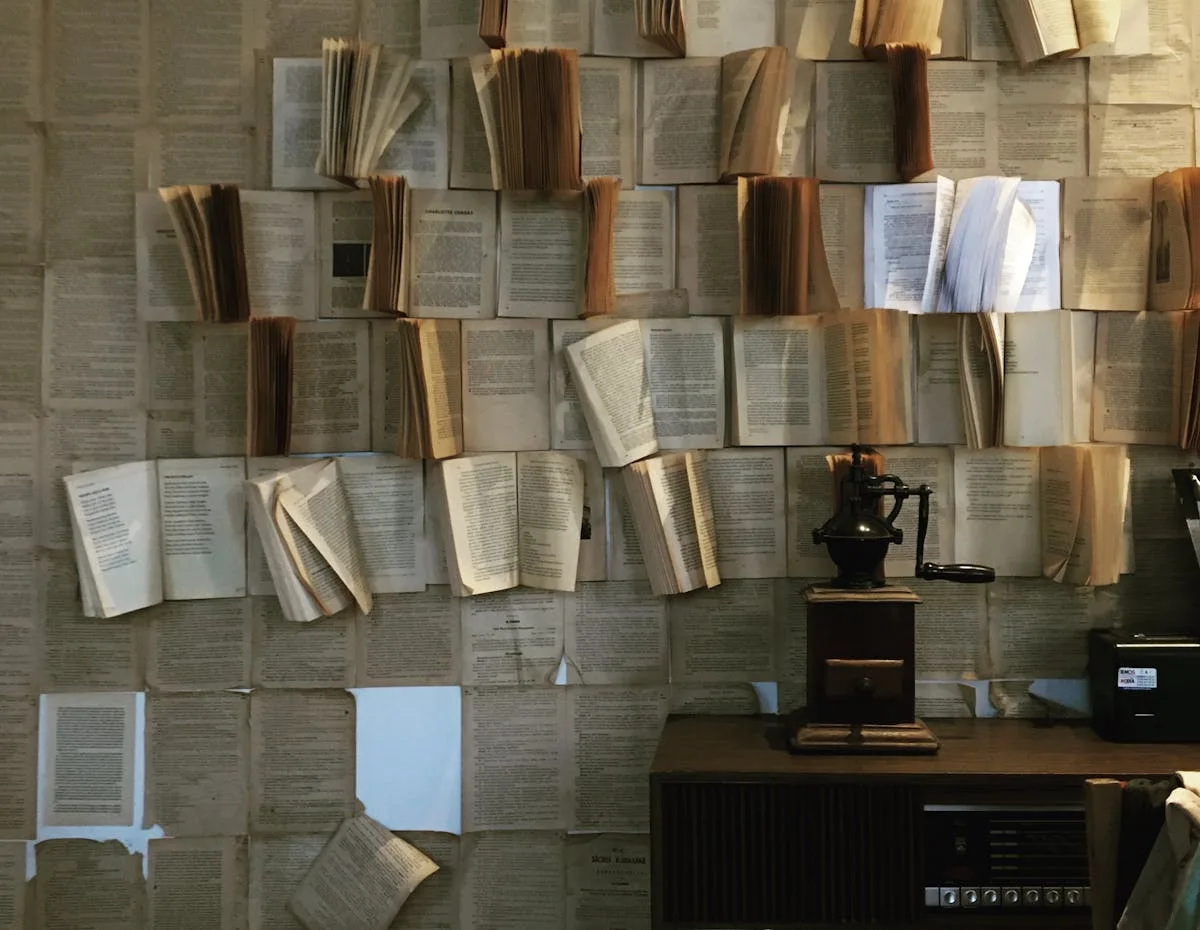 Wall decorated with pages from old books beside a vintage coffee grinder