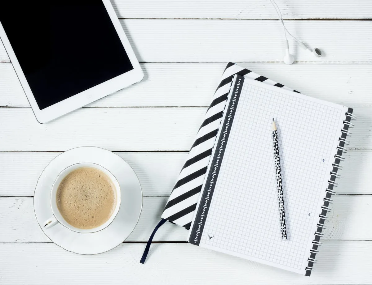 Tablet, notebook and coffee on a bright white desk