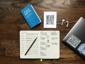 Free Fitness Planner Printables: Track Workouts, Food, and Progress on Paper Handwritten fitness tracker journal with a pencil beside a laptop on a wooden desk