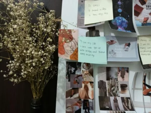 Vision board with handwritten sticky-note goals next to dried baby breath flowers