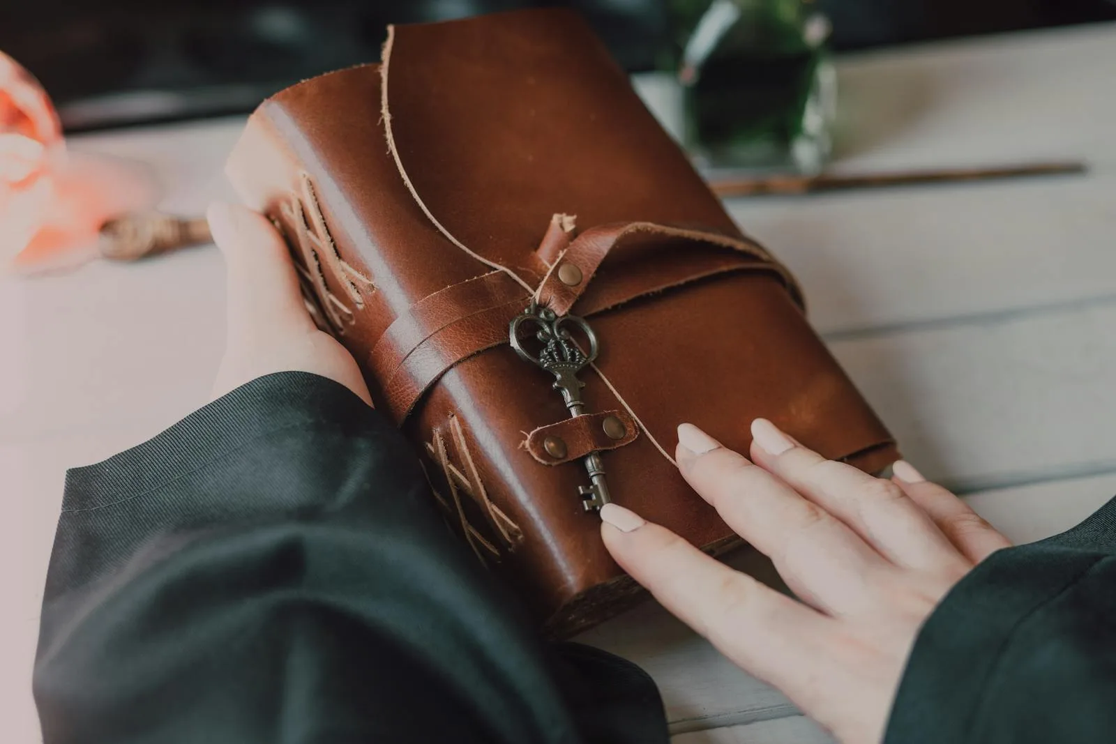 Hands holding a leather-bound junk journal cover with a vintage key and twine