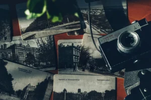 Black-and-white postcards scattered around an old film camera on a dark surface