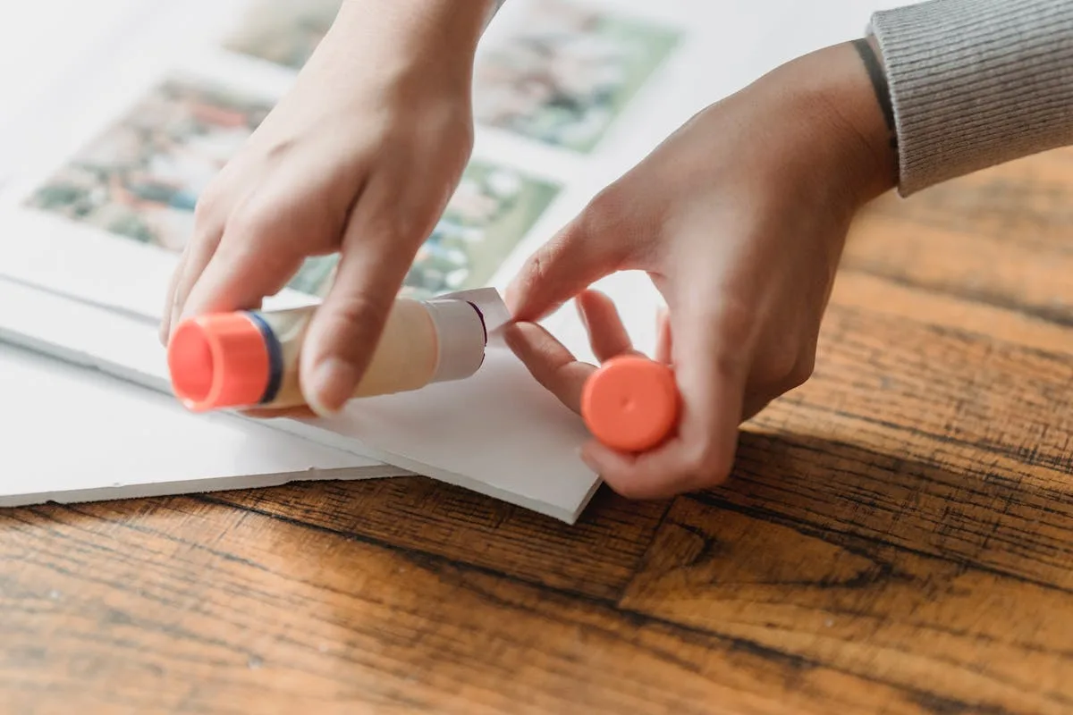 Hands gluing photos and paper scraps into a junk journal