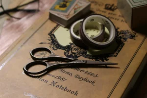 Flat lay of junk journaling supplies, vintage papers, and dry leaves on a handmade journal