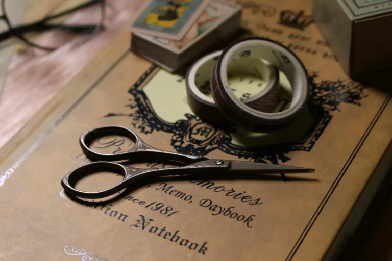 Flat lay of junk journaling supplies, vintage papers, and dry leaves on a handmade journal