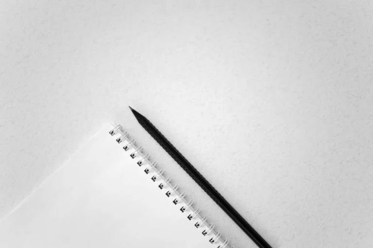 Minimalist white desk with a plain notebook and pen