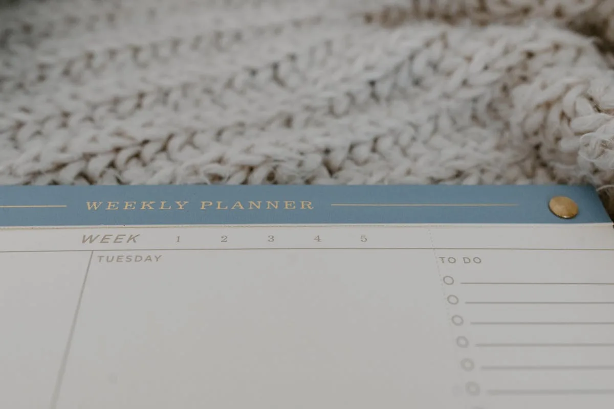 Close-up of a printed weekly planner page with a to-do list beside a knit blanket