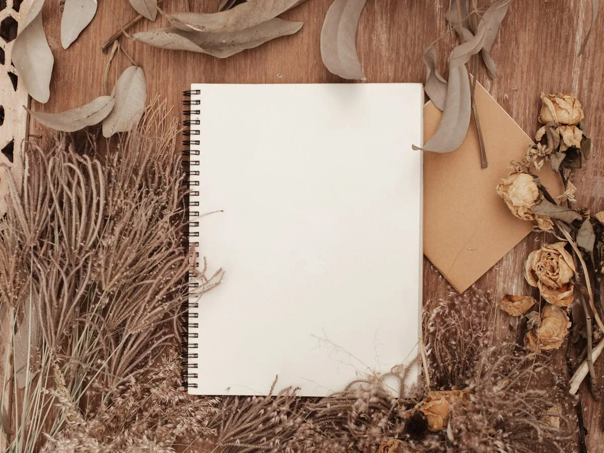 Blank notebook surrounded by dried botanicals and a kraft envelope for a beginner junk journal