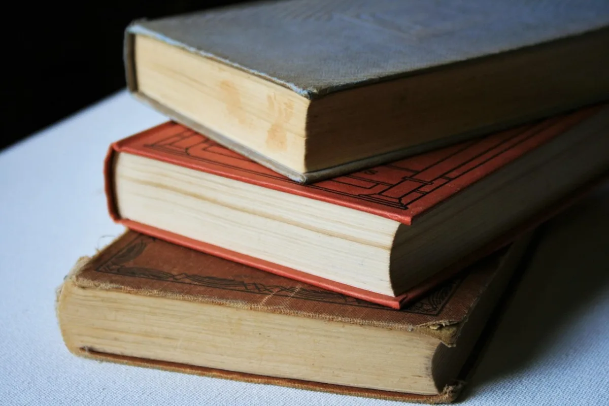 Stack of three vintage hardback books in warm tones