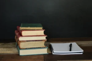 Vision Board Book: The 7 Worth Reading Before You Build Your Next Board Stack of vintage hardcover books beside an open notebook and pen on a wooden desk