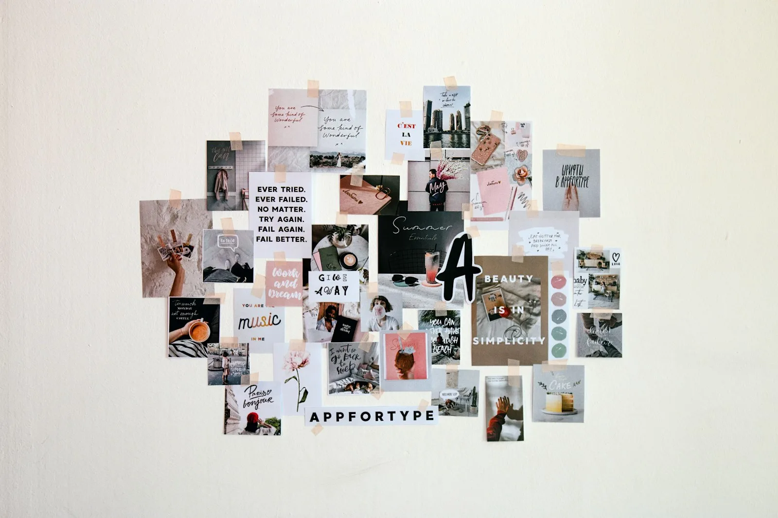 An aesthetic vision board mounted on a white wall with overlapping photo and quote cutouts arranged in an organic cluster