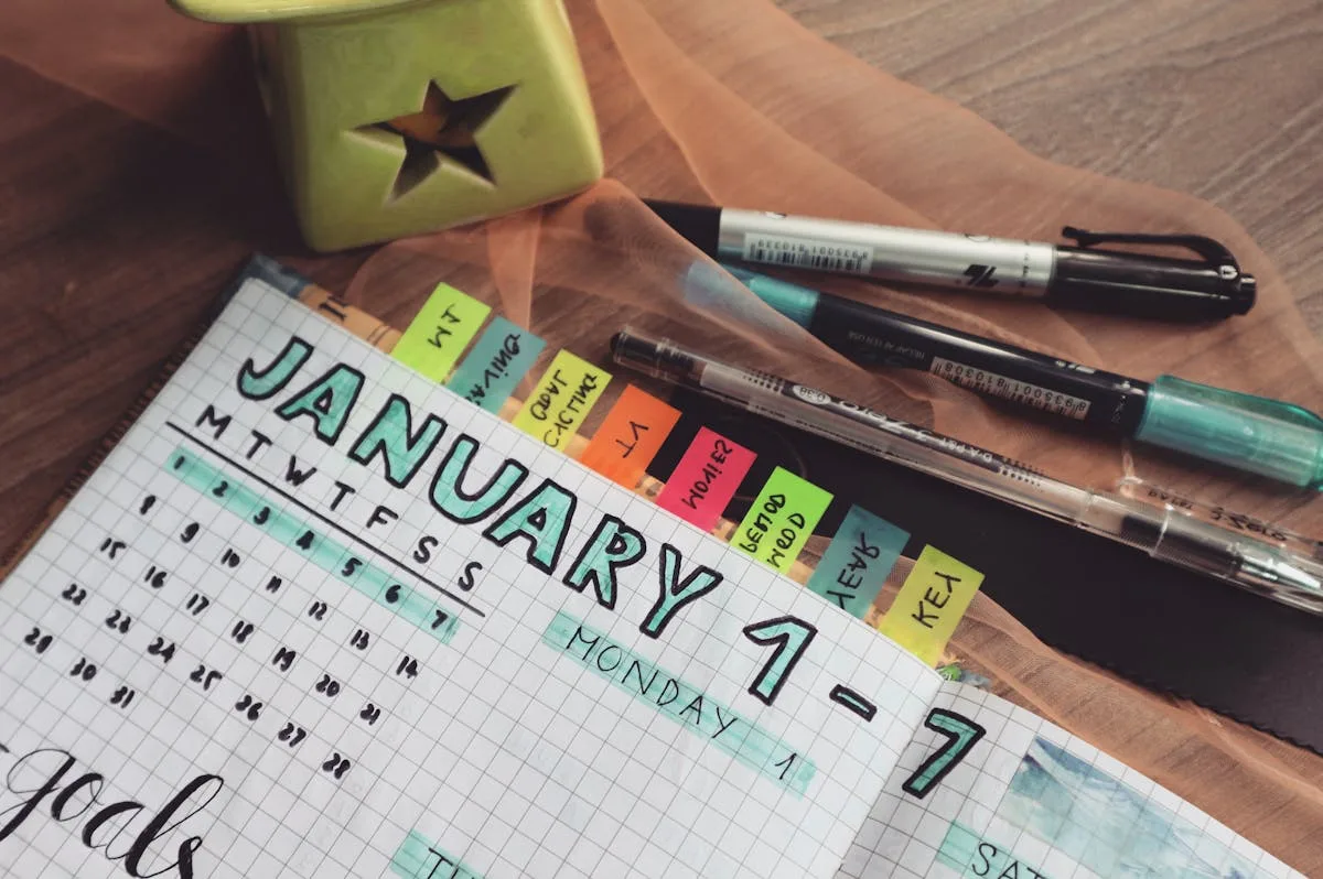 Open weekly planner page with colorful pens laid on top