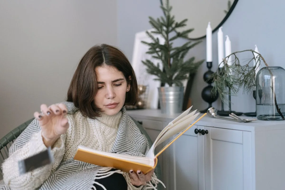 Person looking through a Christmas photo album beside the tree
