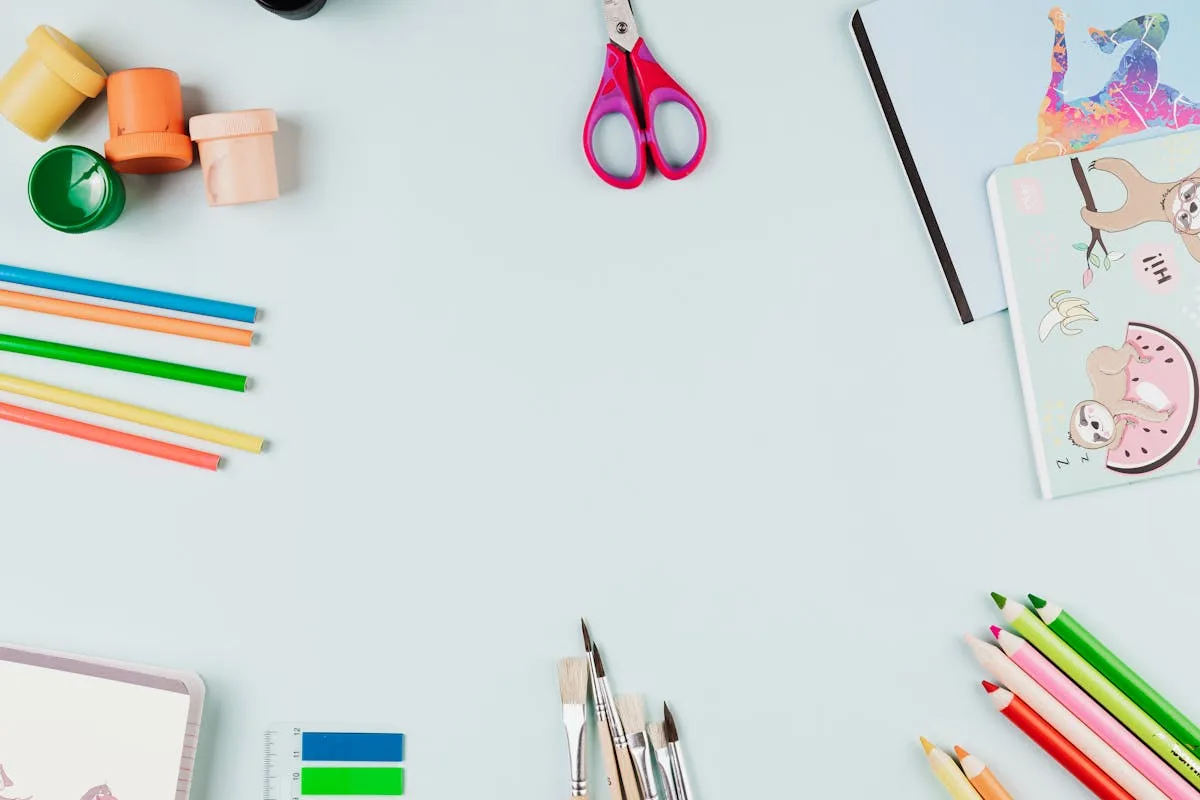 Bright flat lay of colorful pens, pencils and craft stationery on a white desk