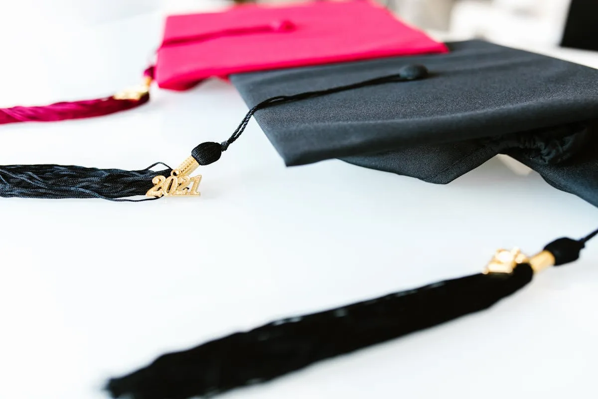 Two graduation caps and tassels with a gold year charm on a white table