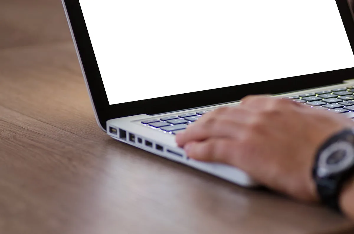 Hands typing on a laptop at a warm wooden desk