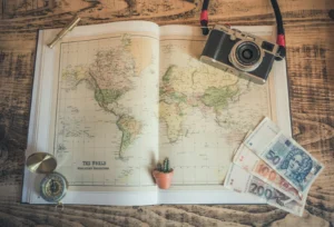 Open travel scrapbook with a map, camera, and printed photos laid out on a desk