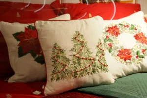 16 Christmas Machine Embroidery Designs (4 Free): Ornaments, Names and Sweatshirts Cushions embroidered with a Christmas tree, poinsettia and wreath on a red sofa