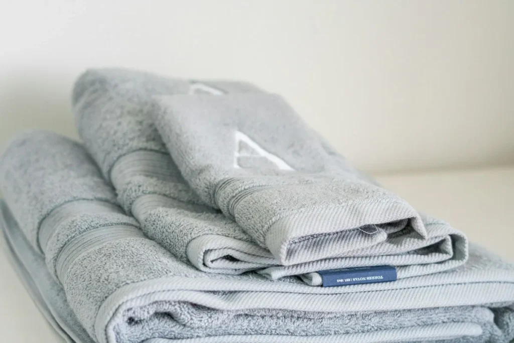 Stack of folded gray bath towels with an embroidered letter monogram